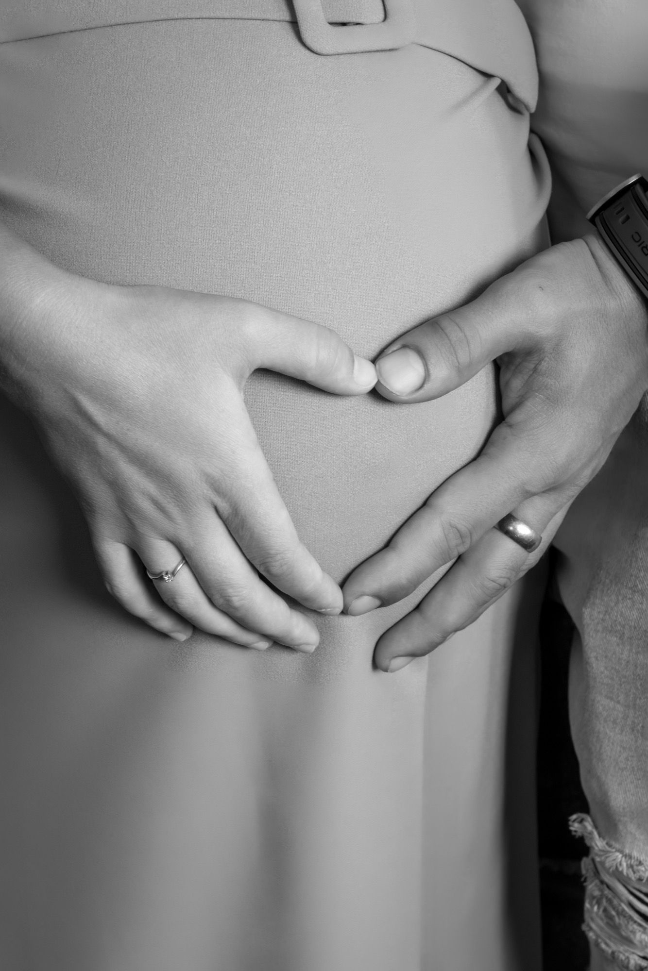 Hände formen ein Herz auf dem Babybauch, Schwarz-Weiß