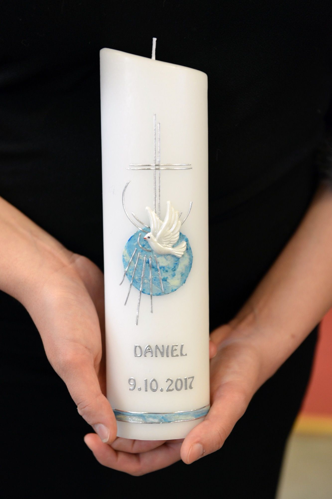 Taufkerze mit Taufsymbol in den Händen