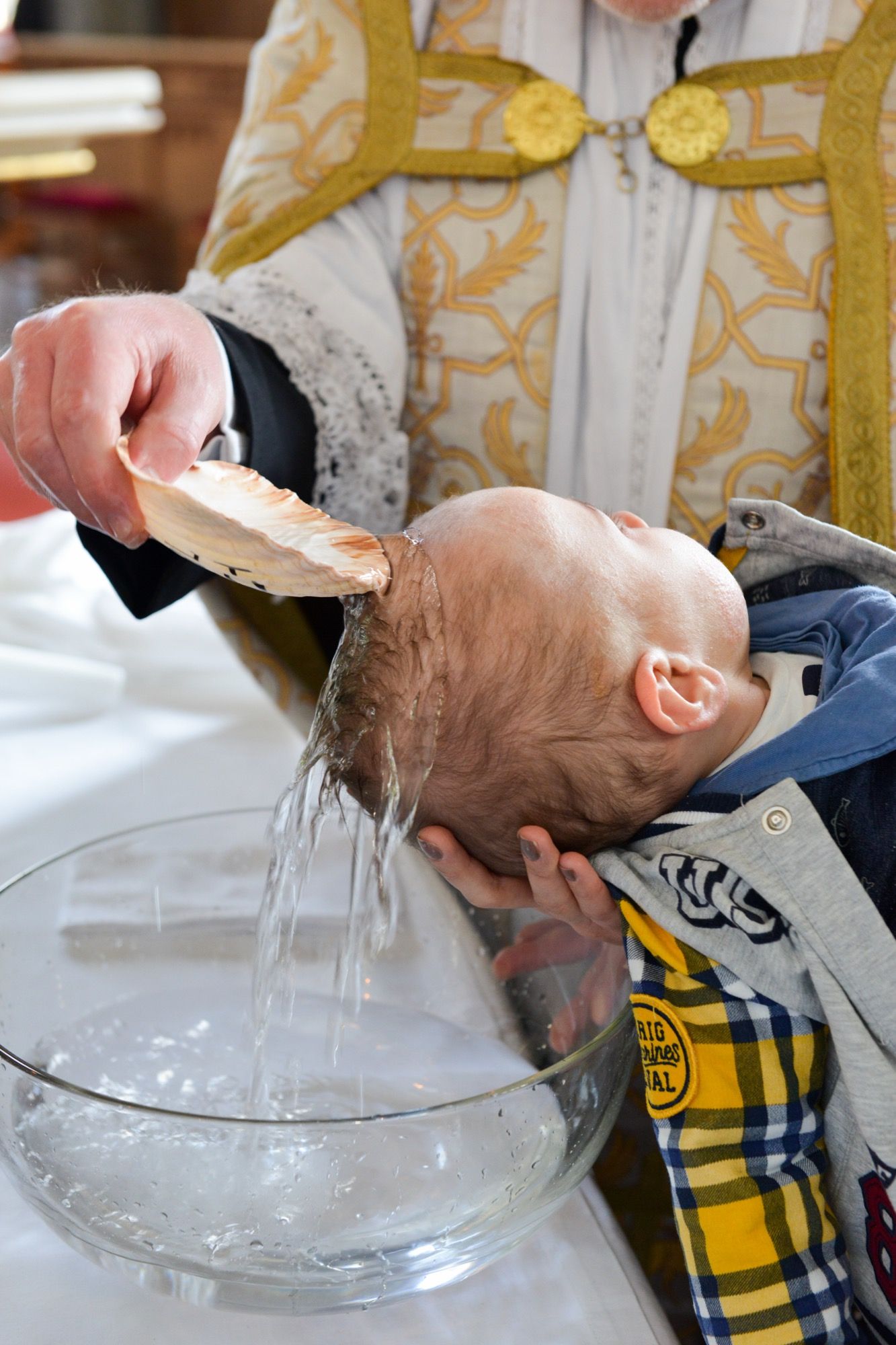 Taufwasser wird über den Kopf des Täuflings gegossen