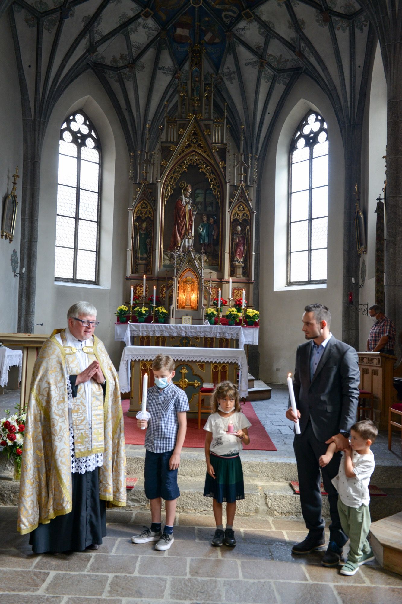 Taufgesellschaft vor dem Hochaltar einer gotischen Kirche